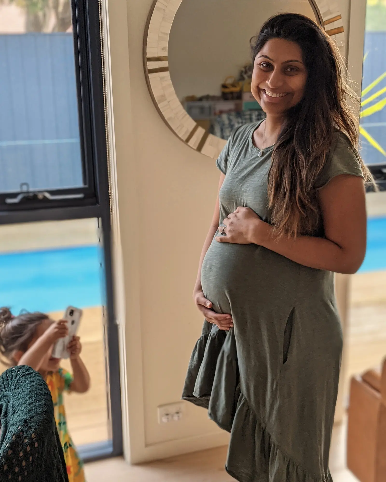 Dr Bhavini Patel, a GP and co-founder of The Iron Infusion Centre, smiling and holding her pregnant belly — representing good iron levels and healthy pregnancy.